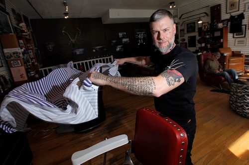 PHIL HOSSACK / WINNIPEG FREE PRESS  - Jeremy Regan shakes out an apron in his Broadway ave Barbershop Tuesday. Jeremy and his shop are celebrating 5 years with a fundraising celbration. The shop has raised over $75,000 already by donating $1/cut to charity. See Martin Cash story. - October 17, 2017