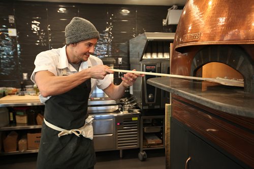 RUTH BONNEVILLE / WINNIPEG FREE PRESS

Red Ember Common co-owner Quinn Ferguson (Steffen Zinn is biz partner),  takes a pizza out of their eye-catching Izzo oven made in Naples which sits in the centre of their newly opened restaurant at the Forks Friday.  The bar top restaurant got its beginnings from The Red Ember Food truck perched on Broadway throughout the summer and now has its second location at the Forks  The neo Neopolitan style pizza's  are all made with fresh, locally sourced ingredients including organic flour from Eli Manitoba, pepperoni from free range Berkshire Pork from Zinn Farms and locally grown produce.  
Standup photo 
Oct 27, 2017