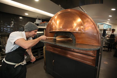 RUTH BONNEVILLE / WINNIPEG FREE PRESS

Red Ember Common co-owner Quinn Ferguson (Steffen Zinn is biz partner),  takes a pizza out of their eye-catching Izzo oven made in Naples which sits in the centre of their newly opened restaurant at the Forks Friday.  The bar top restaurant got its beginnings from The Red Ember Food truck perched on Broadway throughout the summer and now has its second location at the Forks  The neo Neopolitan style pizza's  are all made with fresh, locally sourced ingredients including organic flour from Eli Manitoba, pepperoni from free range Berkshire Pork from Zinn Farms and locally grown produce.  
Standup photo 
Oct 27, 2017