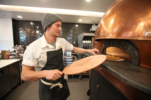 RUTH BONNEVILLE / WINNIPEG FREE PRESS

Red Ember Common co-owner Quinn Ferguson (Steffen Zinn is biz partner),  takes a pizza out of their eye-catching Izzo oven made in Naples which sits in the centre of their newly opened restaurant at the Forks Friday.  The bar top restaurant got its beginnings from The Red Ember Food truck perched on Broadway throughout the summer and now has its second location at the Forks  The neo Neopolitan style pizza's  are all made with fresh, locally sourced ingredients including organic flour from Eli Manitoba, pepperoni from free range Berkshire Pork from Zinn Farms and locally grown produce.  
Standup photo 
Oct 27, 2017