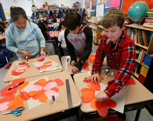 WAYNE GLOWACKI / WINNIPEG FREE PRESS 

From right, Roman, Shiloh and Sarbjit glue their tissue paper petals to create poppies during art class at Tyndall Park Community School Thursday to mark Remembrance Day this weekend. All through the school hallways displayed the  students Remembrance Day art work that included poppies, cemeteries and battle scenes.   Nov. 9 2017