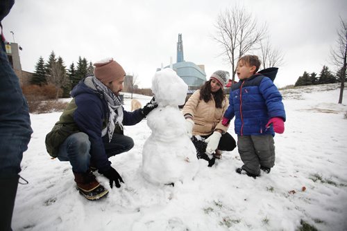 RUTH BONNEVILLE / WINNIPEG FREE PRESS

 Satya (4yrs)  Mapu enjoys  putting the finishing touches on a snow man he made with his little brother Akili (2yrs not in this photo) at the Forks Monday afternoon while spending time with family and friends in the balmy weather. 
Adults in photo are Ivan Arevalo  (left) and Dee Hadi 
Standup photo 

Nov 27, 2017