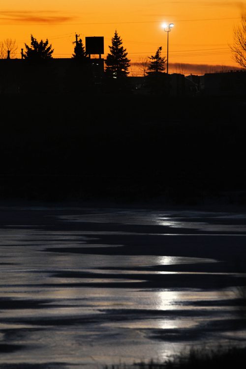 RUTH BONNEVILLE / WINNIPEG FREE PRESS

The orange sky contrasts vividly with the icey blue frozen pond at Woodworth Park creating an interesting view next to Selkirk Ave. Tuesday evening.  
Standup photo 
Nov 28, 2017