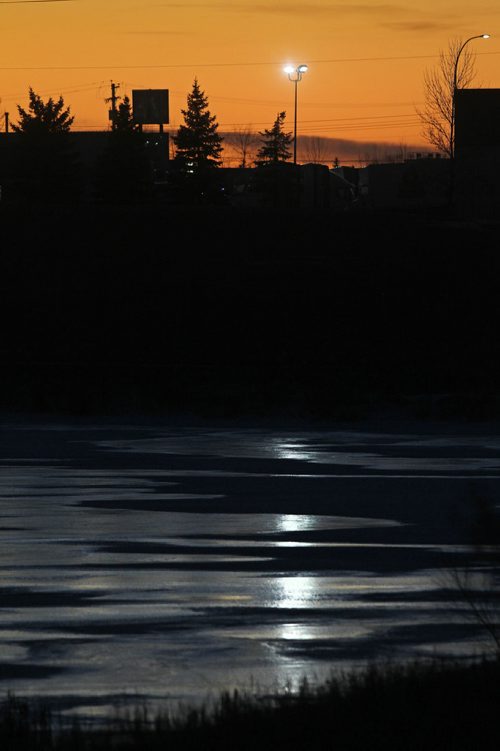 RUTH BONNEVILLE / WINNIPEG FREE PRESS

The orange sky contrasts vividly with the icey blue frozen pond at Woodworth Park creating an interesting view next to Selkirk Ave. Tuesday evening.  
Standup photo 
Nov 28, 2017