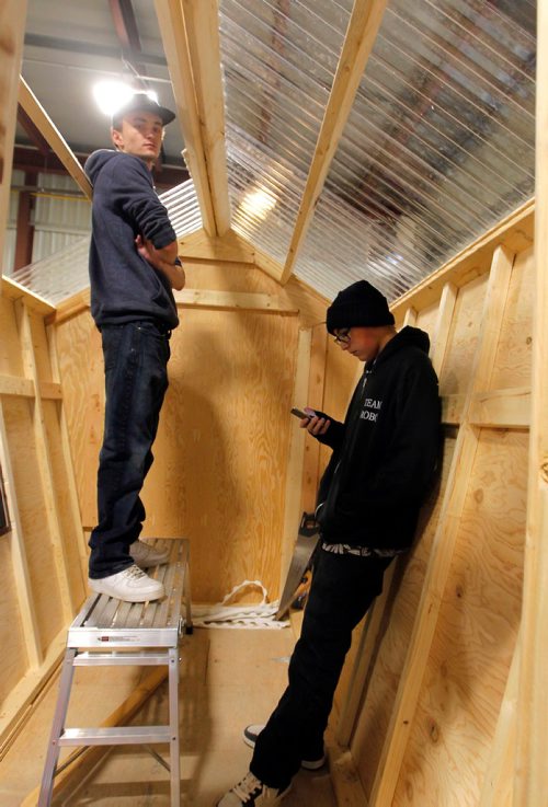 BORIS MINKEVICH / WINNIPEG FREE PRESS
ART ON ICE - Students Jordan Kupchik, left, and Brian Sanderson, right, inside an ice fishing shack they are helping build. The Lord Selkirk Learning Centre is building ice fishing shacks that will be auctioned off.  The proceeds of the artful shacks is a fundraiser for the Homes for all Fund at the Selkirk & District Community Foundation. They are building this one in a borrowed space indoors at a City of Selkirk Works and Operations department. There are 6 shacks in total that the community helped fund and paint. STANDUP PHOTO Nov. 29, 2017