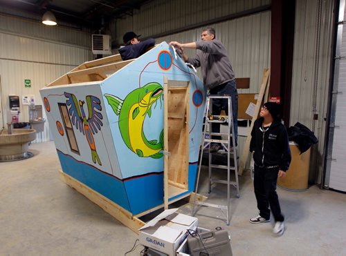 BORIS MINKEVICH / WINNIPEG FREE PRESS
ART ON ICE - Teacher/instructor John Bukich, on ladder, works with students Jordan Kupchik, left, and Brian Sanderson, right, on an ice fishing shack. The Lord Selkirk Learning Centre is building ice fishing shacks that will be auctioned off.  The proceeds of the artful shacks is a fundraiser for the Homes for all Fund at the Selkirk & District Community Foundation. They are building this one in a borrowed space indoors at a City of Selkirk Works and Operations department. There are 6 shacks in total that the community helped fund and paint. STANDUP PHOTO Nov. 29, 2017