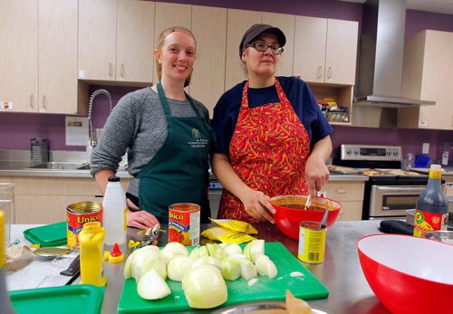 BORIS MINKEVICH / WINNIPEG FREE PRESS
Sonia Cashman, right, a single Indigenous mother who used to depend on the West Central Womens Resource Centre prepares a meal that she will serve Friday for lunch for the entire centre. Shes done so several times previously, starting in 2014. Left is WCWRC director of communications and fundraising Denise MacDonald. ERIK PINDERA STORY Nov. 30, 2017