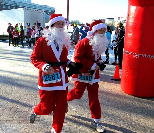 BORIS MINKEVICH / WINNIPEG FREE PRESS
The annual 5K Santa Shuffle Fun Run at The Forks brings families and friends together. The event is held across North America to help The Salvation Army to assist families and individuals in need during the Christmas season and throughout the year. From left dressed as santa claus', Amanda Wrubleski and her mom Anita Wrubleski cross the finish line. There were 530 entries in the race. STANDUP PHOTO  Dec. 2, 2017