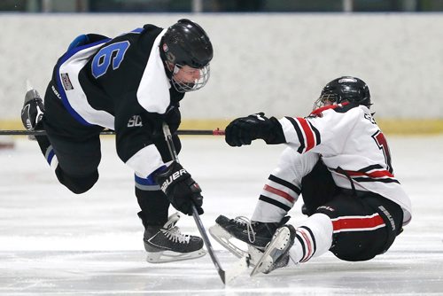JOHN WOODS / WINNIPEG FREE PRESS
A College Beliveau (white) player is checked by a Sanford (black) player in a high school league game at Southdale Community Centre Monday, December 11, 2017. Despite being assisted off the ice the player was back on the ice at the next shift change.