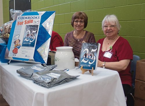 Canstar Community News Dec. 7, 2017 - (From left) Shirley McDonald, head of the cookbook committee, and Kathi O'Shaugnessy, silver anniversary committee member, sold cookbooks at the Good Neighbours' 25th anniversary tea. (SHELDON BIRNIE/CANSTAR/THE HERALD)