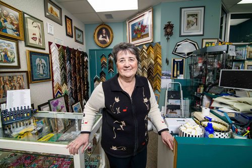 Sheena Buckner, owner of Sheenas Needle Art Gallery leaning over her gallerys counter for one of the last times. Dec. 21, 2017 Mike Sudoma / Winnipeg Free Press