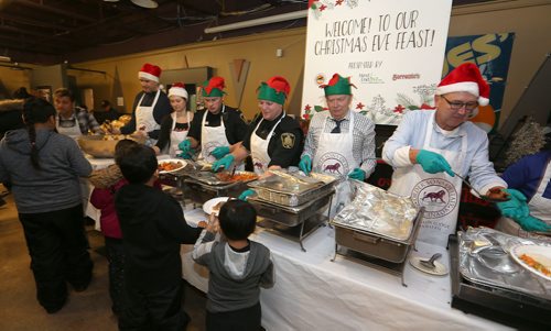 JASON HALSTEAD / WINNIPEG FREE PRESS

L-R: Charlie McDougall, Kathryne Cardwell, Const. Tyson Burch, Const. Max Desjardins, Barry Hoeppner and John Ward serve up the food at the X-Cues Café, West End BIZ, Sons of Italy and Sorrento's On Ellice 12th annual Christmas eve dinner at X-Cues Café on Sargent Avenue in the West End on Dec. 24, 2017. (See Social Page)