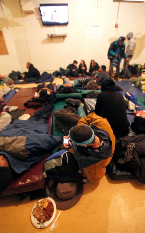 PHIL HOSSACK / Winnipeg Free Press -  Safe, warm and a hot meal waiting a homeless man plays a video game laying on his communal bed Thursday evening at the Winnipeg Project's shelter. See Jen Zorati's story. -   January 4, 2018