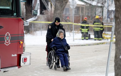 TREVOR HAGAN / WINNIPEG FREE PRESS
A Winnipeg Police officer assists an area resident as she needed to cross the street near an active fire on the 400 block of Flora, Sunday, January 7, 2018.