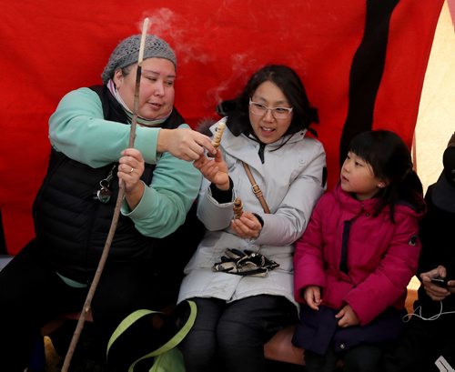 TREVOR HAGAN / WINNIPEG FREE PRESS
Melissa Nepinak demonstrates how to make bannock with Uyung Woon and Irene Cha, 5, at The Forks, Sunday, January 21, 2018.