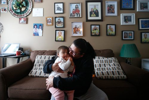 JOHN WOODS / WINNIPEG FREE PRESS
Mary Burton, who works to empower people who are in the Child and Family Services (CFS) system, cuddles her granddaughter in front of her family "wall of fame" in her Winnipeg home Sunday, January 21, 2018. Burton co-founded Fearless R2W three years ago,  which supports CFS clients and is named after the North End postal code frequently visited by Child and Family Services agents.