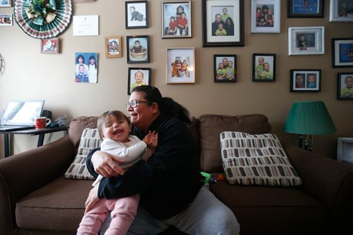 JOHN WOODS / WINNIPEG FREE PRESS
Mary Burton, who works to empower people who are in the Child and Family Services (CFS) system, cuddles her granddaughter in front of her family "wall of fame" in her Winnipeg home Sunday, January 21, 2018. Burton co-founded Fearless R2W three years ago,  which supports CFS clients and is named after the North End postal code frequently visited by Child and Family Services agents.