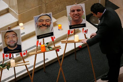 JOHN WOODS / WINNIPEG FREE PRESS
Mohamed Al-Tasi places a rose under a photo of Abdelkrim Hassane during an anniversary memorial for Hassane, Azzeddine Soufiane, Khaled Belkacemi, Mamadou Tanou Barry, Ibrahima Barry and Aboubaker Thabti, at the Manitoba Legislature in Winnipeg Monday, January 29, 2018. The six Muslim men were shot dead in a Quebec city mosque January 29, 2017.