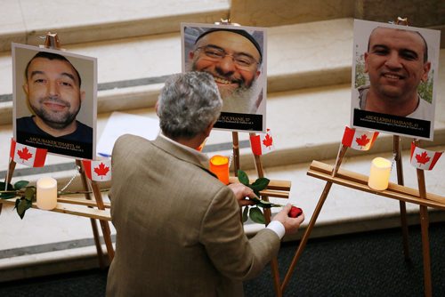 JOHN WOODS / WINNIPEG FREE PRESS
Abdo Al-Tasi places a rose under a photo of Azzeddine Soufiane during an anniversary memorial for Soufiane, Khaled Belkacemi, Mamadou Tanou Barry, Ibrahima Barry, Aboubaker Thabti,  and Abdelkrim Hassane at the Manitoba Legislature in Winnipeg Monday, January 29, 2018. The six Muslim men were shot dead in a Quebec city mosque January 29, 2017.