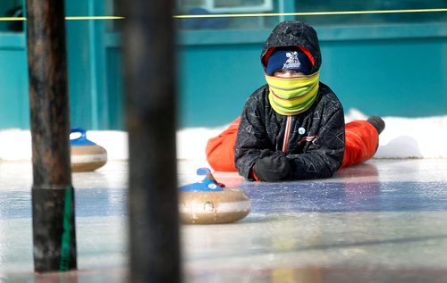 PHIL HOSSACK / Winnipeg Free Press - Stand-Up - 9 Yr old Nathan Kendall peers out from underneath his winter geat watching his shot on the Crokinole/curling ice at the Forks Saturday afternoon. He and his brother Andrew were warming up for their match in the weekend tournament. -  February 10, 2018