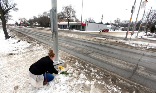 PHIL HOSSACK / WINNIPEG FREE PRESS - An area resident, a woman who didn't want her name used lays a rose at the scene of a young boy's death at Varennes ave and St Annes Rd Tuesday afternoon. See story. February 13, 2018