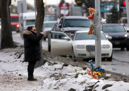 PHIL HOSSACK / WINNIPEG FREE PRESS - A passerby uses her phone to document the growing memorial cairn at the site of a young boy's death at Varennes ave and St Annes Rd Tuesday afternoon. See story. February 13, 2018