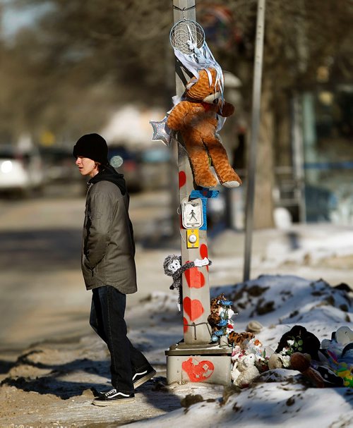 PHIL HOSSACK / WINNIPEG FREE PRESS - A pedestrian waits for traffic to stop before crossing beside cairn of thoughts prayers and toys grows at the crosswalk scene of an accident that killed 8 yr old Surafel last tuesday. See Redekop story.- February 17, 2018