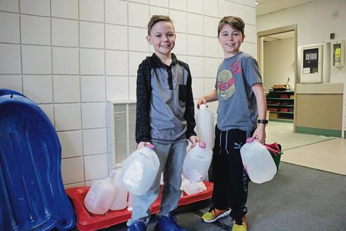 Canstar Community News Feb. 13, 2018 - Adysen Baird (right) and Matthew Kemerle (left) hold the milk jugs they used to flood the ice rink they built at Collicutt Schools backyard. (LIGIA BRAIDOTTI/CANSTAR/TIMES)