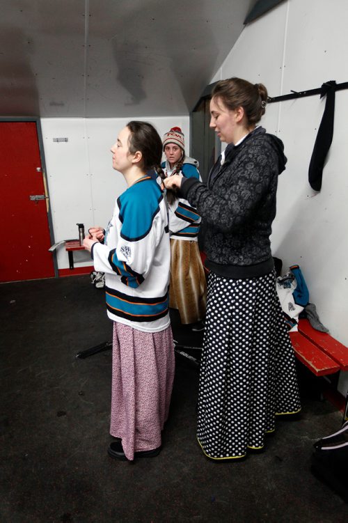 PHIL HOSSACK / WINNIPEG FREE PRESS - Doris Wurtz waits while her sister Tabitha braids her hair. Another sister Anya gets settled in the MacGregor arena dressing room for the annual charity game. See Melissa Martin's story. February 23, 2018