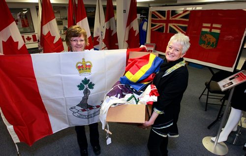 BORIS MINKEVICH / WINNIPEG FREE PRESS
Argyle Museum Settlers, Rails & Trails Inc flag museum in the Argyle Community Centre. From left, Carol Morgan (holding the Royal Military College flag) and Joan Grandmont with some flags donated . BILL REDEKOP STORY Feb. 28, 2018