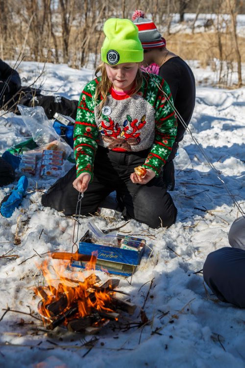 MIKE DEAL / WINNIPEG FREE PRESS
Chloë Galenzoski, 12, cooks a hotdog for a fellow team member over the camp fire during a lunch break with other members of the 82nd Pathfinders "She Wolves".
350 youth will compete this weekend in the 47th annual Klondike Derby at Scouts Canada's Camp Amisk, just south of the Perimeter Highway. They will demonstrate winter survival skills, learn teamwork and "make new friends." Hosted by Scouts Canada, the Klondike Derby features teams of six to eight Cub Scouts, Girl Guides, Scouts and Pathfinders pulling a Klondike-style sleigh on a 2.5-km journey through the woods. 
180303 - Saturday, March 03, 2018.