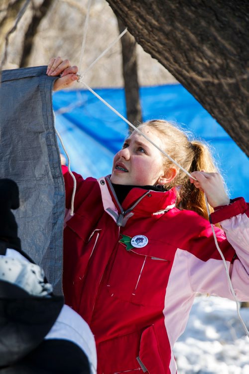 MIKE DEAL / WINNIPEG FREE PRESS
Lauren Teller, 14, ties a tarp to a tree to create a temporary shelter during a lunch break while other members of the 82nd Pathfinders "She Wolves" chop wood, start a camp fire and cook food in the woods.
350 youth will compete this weekend in the 47th annual Klondike Derby at Scouts Canada's Camp Amisk, just south of the Perimeter Highway. They will demonstrate winter survival skills, learn teamwork and "make new friends." Hosted by Scouts Canada, the Klondike Derby features teams of six to eight Cub Scouts, Girl Guides, Scouts and Pathfinders pulling a Klondike-style sleigh on a 2.5-km journey through the woods. 
180303 - Saturday, March 03, 2018.