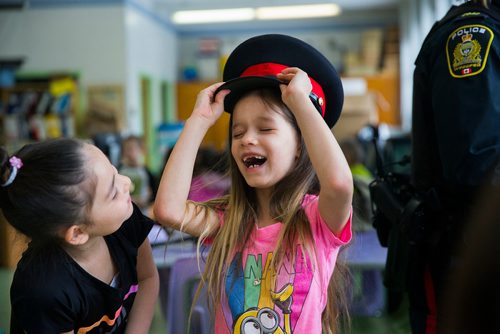 MIKAELA MACKENZIE / WINNIPEG FREE PRESS
Natalia Catcheway, six, tries on a police hat as her friend, Rhyleigh Peebles, eight, watches at an activity where women in various fields of work came in and talked to children on Women's Day at Weston School in Winnipeg, Manitoba on Thursday, March 8, 2018.
180308 - Thursday, March 08, 2018.