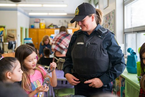 MIKAELA MACKENZIE / WINNIPEG FREE PRESS
Constable Leonie Lazarus watches as Rhyleigh Peebles, eight (left), and Natalia Catcheway, six, take a look at handcuffs at an activity where women in various fields of work came in and talked to children on Women's Day at Weston School in Winnipeg, Manitoba on Thursday, March 8, 2018.
180308 - Thursday, March 08, 2018.