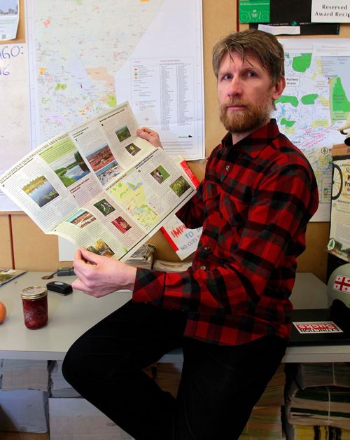 BORIS MINKEVICH / WINNIPEG FREE PRESS
Green Page - For story about the effects of climate change, specifically the effects on the eco-system here in Manitoba. Eric Reder from Wilderness Committee poses for a photo in his office with a publication they put out on the topic. He is a climate change expert with the Western Canada Wilderness Committee.  March 13, 2018