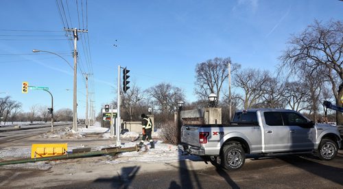 MIKE DEAL / WINNIPEG FREE PRESS
A city traffic maintenance worker installs a new traffic light after a pickup truck crashed into it in front of the Assiniboine Park sign on Corydon and Shaftesbury this morning. 
180315 - Thursday, March 15, 2018.