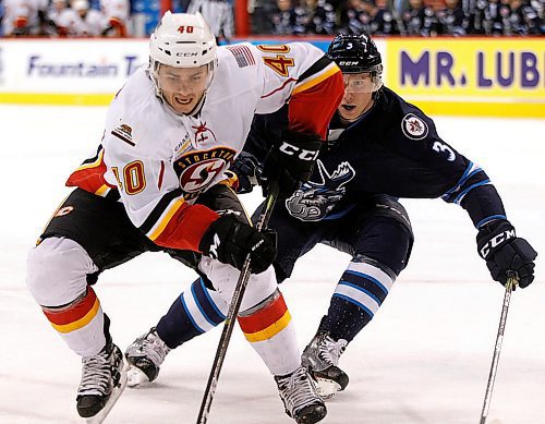 PHIL HOSSACK / WINNIPEG FREE PRESS - Stockton Heat #40 Darren Nowick looks for the puck with Manitoba Moose #3 Jan Kostalek on his tail Thursday evening at the Bell MTS Place. - March 22, 2018