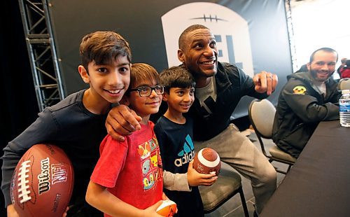PHIL HOSSACK / WINNIPEG FREE PRESS - Look where?? Adarius Bowman works with a trio of young fans as he signs souviniers at the CFL Week's Autograph session Friday afternoon. left to right, Vinjay Gupta, Jai Bahl and Sanjay Gupta all brought their favorite football to the autograph session. CFL player Weston Dressler looks up from his autographs, right. See story?.- March 23, 2018