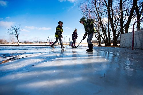 MIKAELA MACKENZIE / WINNIPEG FREE PRESS
Caleb (left), Kyla, and Adam Nobel play a game of hockey in their boots on their backyard rink in Transcona in Winnipeg on Wednesday, March 28, 2018.
Mikaela MacKenzie / Winnipeg Free Press 28, 2018.