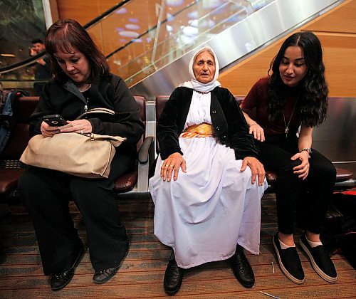 PHIL HOSSACK / WINNIPEG FREE PRESS - Overwhelmed by travel and welcome, Family matriarch Shireen Khudida (centre left) had to take a seat in the midst of the throngs of Yazidi's who came to Richardson International Airport Thursday to welcome the matriarch and the last of "Operation Ezra's" Yazidi families to Winnipeg and Canada. See Carol Sanders story. - March 29, 2018