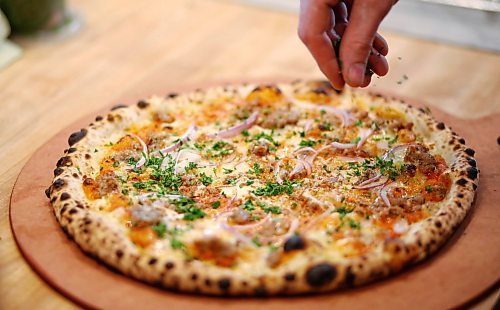 MIKE DEAL / WINNIPEG FREE PRESS
MUNCH MADNESS - Red Ember Pizza at The Forks. A Happy Pig pizza that has vodka sauce, red onion, house pork sausage, fontina and parsley on it. 
180405 - Thursday, April 5, 2018