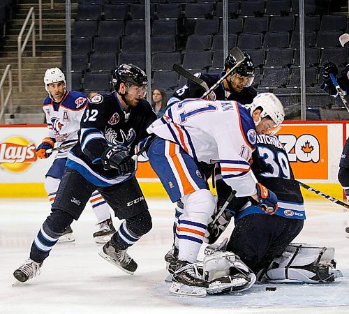 PHIL HOSSACK / WINNIPEG FREE PRESS - Manitoba Moose #32 Jansen Harkins pushes away Bakersfield Condor #11 Colin Larkin as Moose netminder Michael Hutchinson looses the puck behind his pads Friday night at the Bell Mts Centre in Winnipeg. See story. - April 6, 2018