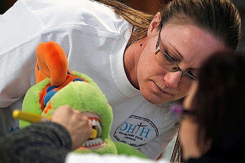 PHIL HOSSACK / WINNIPEG FREE PRESS - Twyla Braybrook demonstrates proper brushing technique on a stuffed dinosaur Saturday at the fifth annual Sharing Smiles Day on Saturday at the University of Manitobas Bannatyne campus.
organized by dentistry and dental hygeinist students the event promotes dental health for Manitobans with Special needs.  Twyla's daughter Haley was chasing bubbles at the event. See photo. - April 14, 2018

