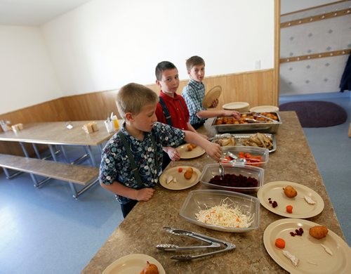 PHIL HOSSACK/Winnipeg Free Press - Three young  elementary students at the James Valley Hutterite Colony settles into their lunch in the children's dining room Tuesday. Children from the age of 5 -15 eat separately from their parents who dine in a separate room at the community's main kitchen hall.  James Valley Hutterite Colony home.  One of the original Hutterite settlements in Manitoba the James Valley community celebrates it's 100th Anniversary this year.  -  April 24, 2018