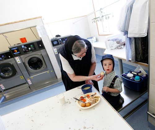 PHIL HOSSACK/Winnipeg Free Press - 21/2 yr old Edward gets served his lunch in the communal laundry by his grandmother Mary HoferTuesday at the James Valley Hutterite colony. Kids under five are fed at home or elsewhere by parents and caregivers, Children from the age of 5 -15 eat separately from their parents who dine in a separate room at the community's main kitchen hall.  James Valley Hutterite Colony home.  One of the original Hutterite settlements in Manitoba the James Valley community celebrates it's 100th Anniversary this year.  -  April 24, 2018