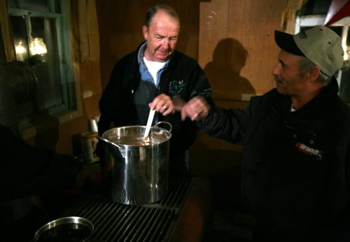 Brandon Sun Delnor Davies stirs a pot of hot chocolate while talking with friend Wayne Drummond Tuesday evening. The spirit of the now-former town of Bernice lives on in a century-old, one-room schoolhouse, which was the site of the 11th annual Christmas concert for the surrounding area. (Colin Corneau/Brandon Sun)