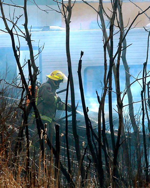 BORIS MINKEVICH / WINNIPEG FREE PRESS
A grass fire spreads to a portable office on the site of Industrial Trailer Sales & Rentals on Fermor just east of Lakeside Road. In this photo a firefighter works to put out some hot spots on the property. Extreme wind has made the fire hard to fight. April 29, 2018
