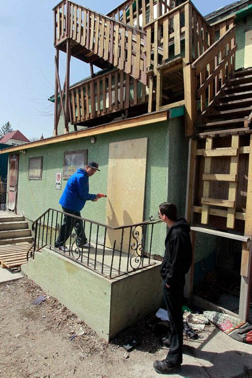 BORIS MINKEVICH / WINNIPEG FREE PRESS
Rooming house fire at 57 Lily Street. From left, resident Andre Sinclair takes off the board covering his door while is brother Shaun Chihonik watches. He took the board off so he could get cloths and food from his fridge. ALEXANDRA PAUL STORY. April 29, 2018