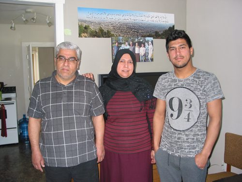 Canstar Community News April 23, 2018 - (From left) Hassim, Sheren and their son Mohamed Bakr stand in front of a family photo taken in Turkey before Hassim and Sheren and three of their six children came to Portage la Prairie in November 2016. (ANDREA GEARY/CANSTAR COMMUNITY NEWS)