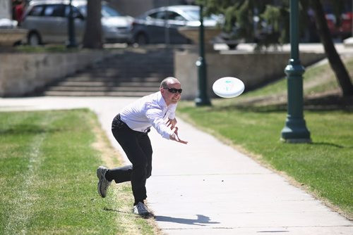 MIKE DEAL / WINNIPEG FREE PRESS
Mario Markmann tosses a frisbee around with a friend during a break at work on the grounds of the Manitoba Legislative Building Monday afternoon as the temperature pushes into the 31C territory. 
180507 - Monday, May 7, 2018.